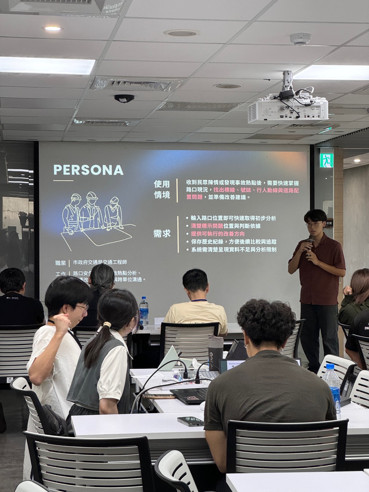 簡報者在投影幕旁講解使用情境與需求