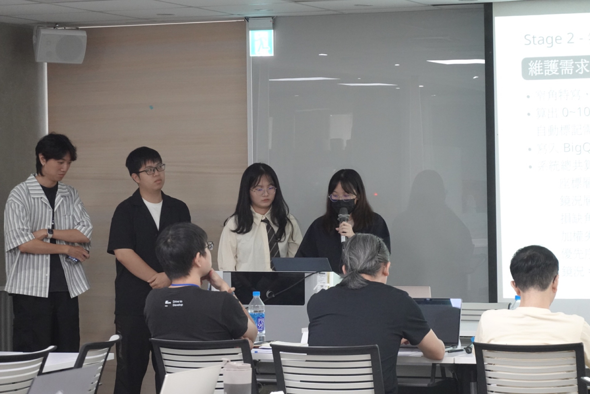 四位組員站在投影幕前輪流簡報
